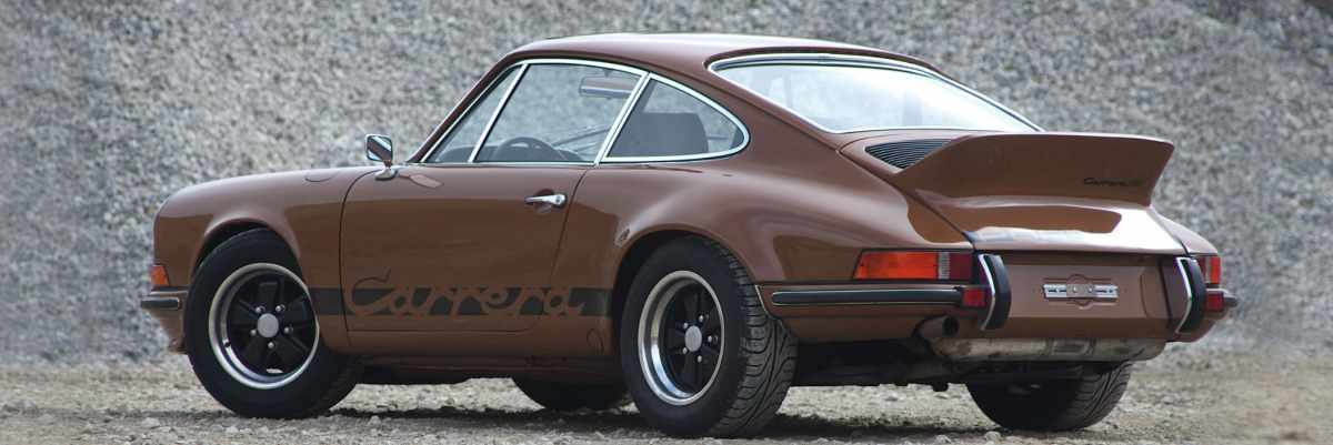 A brown Porsche 911 Carrera RS on gravel